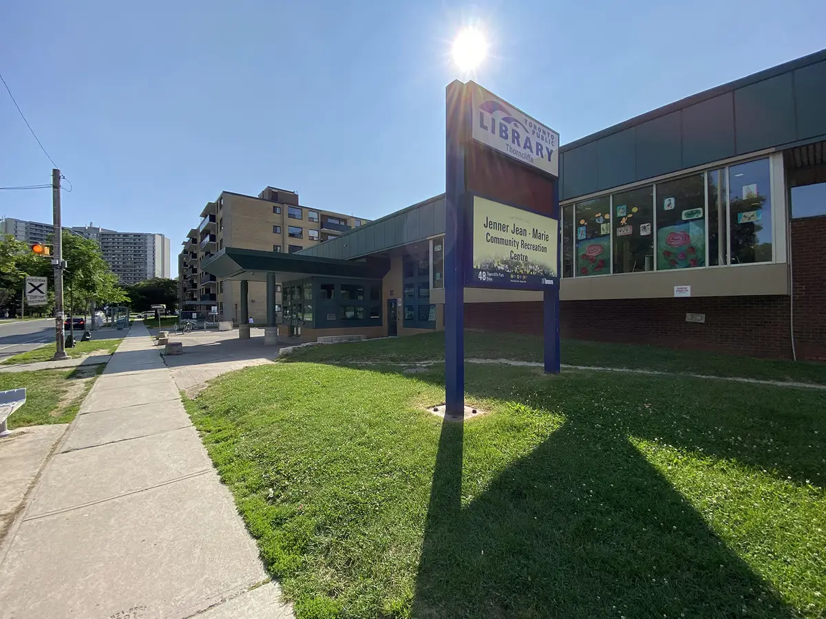 Toronto Public Library Thorncliffe branch sign beside the Jenner Jean-Marie Community Recreation Centre sign, with the building entrance behind