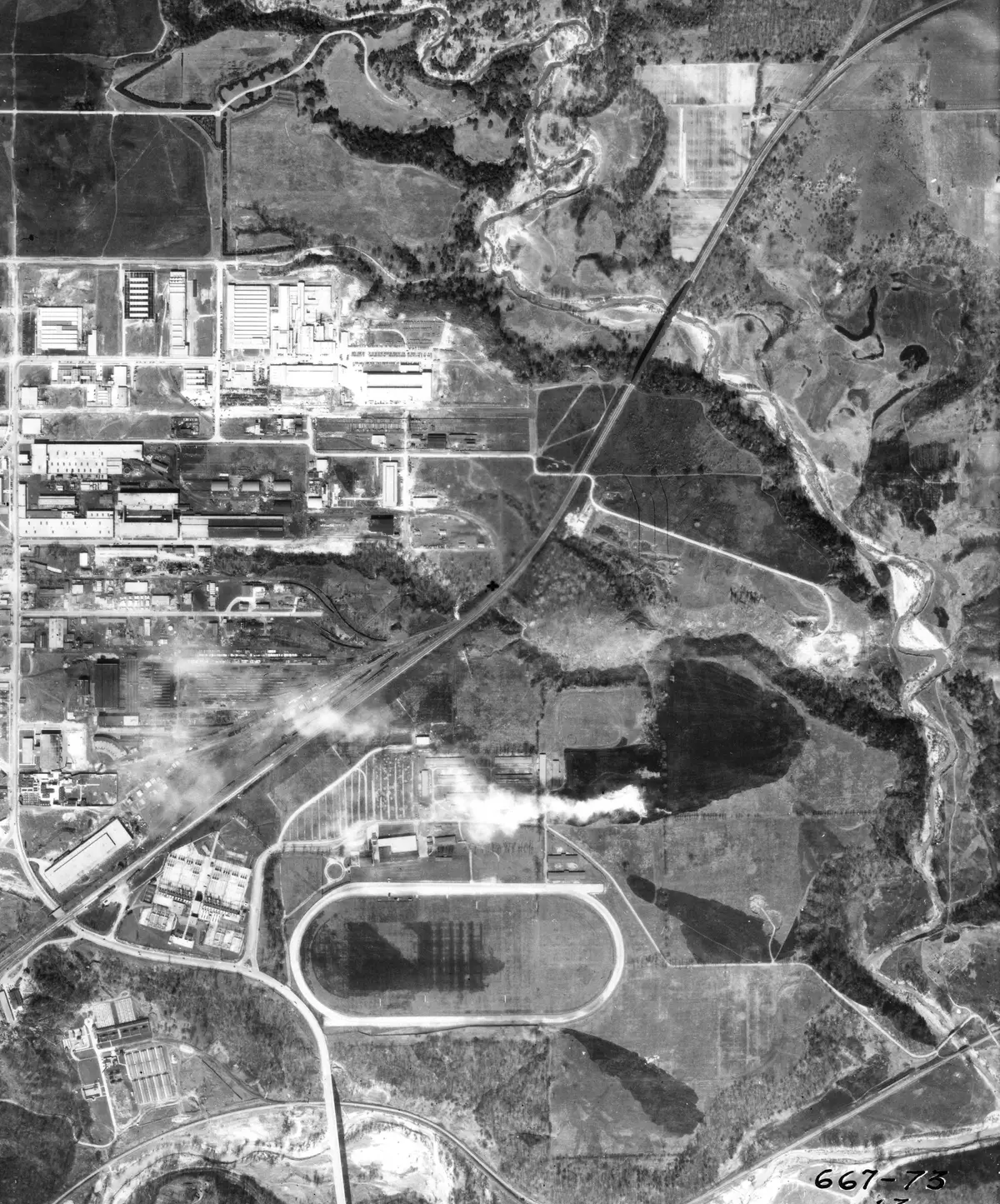 Black-and-white aerial photograph of Thorncliffe in 1942, with an oval track in the lower centre and industrial buildings to the upper left