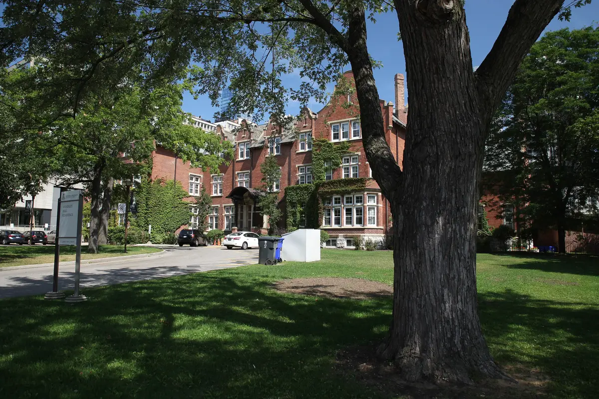 Red-brick Annesley Hall with its gabled facade and a large tree on the lawn in front
