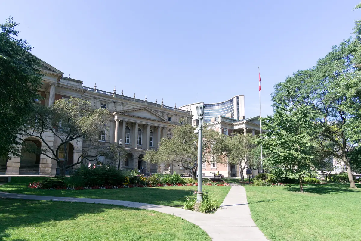 The columned front of Osgoode Hall across a green lawn, with a path and mature trees