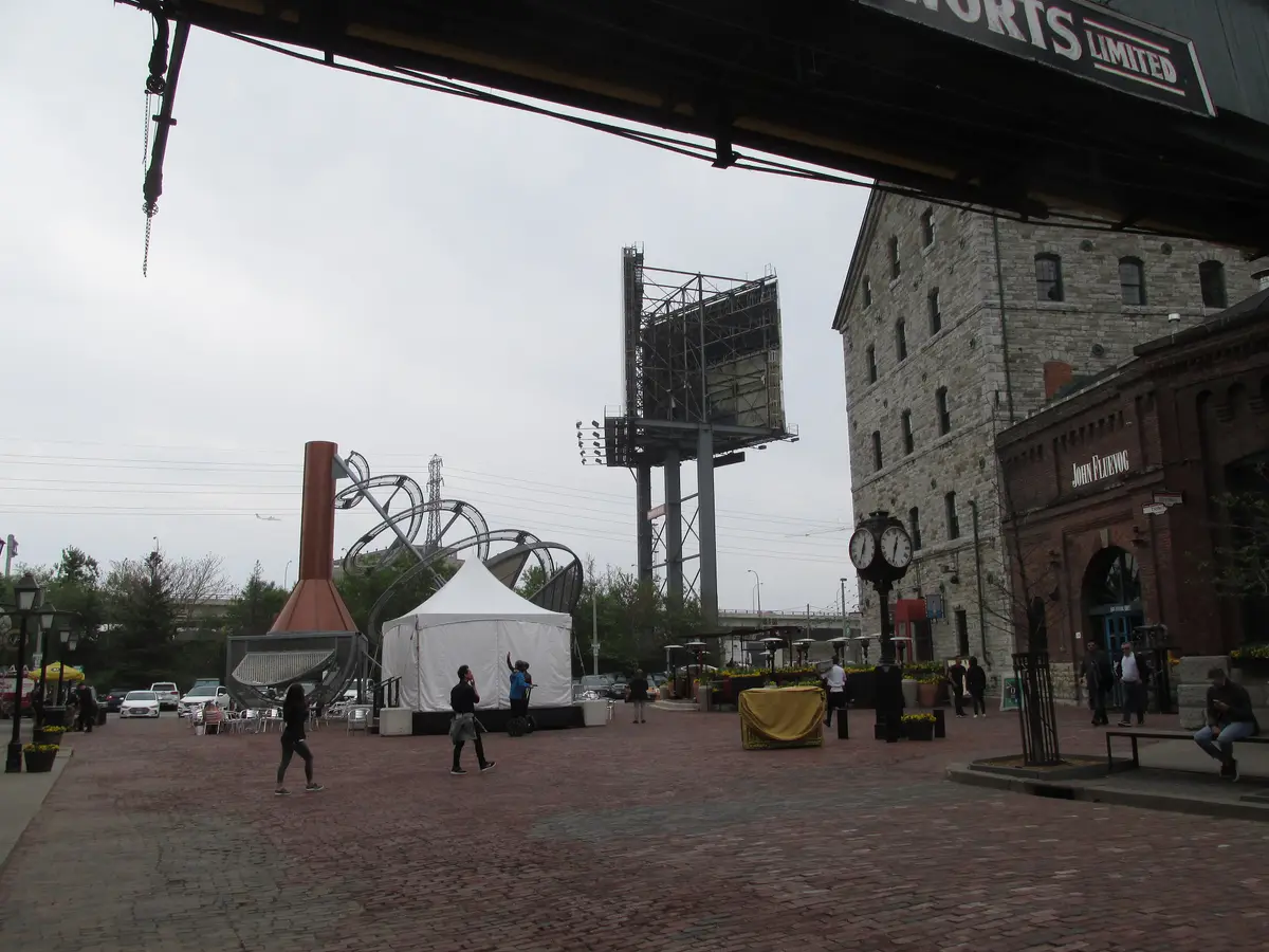 A brick-paved square in the Distillery District with a white tent, a street clock and old stone buildings