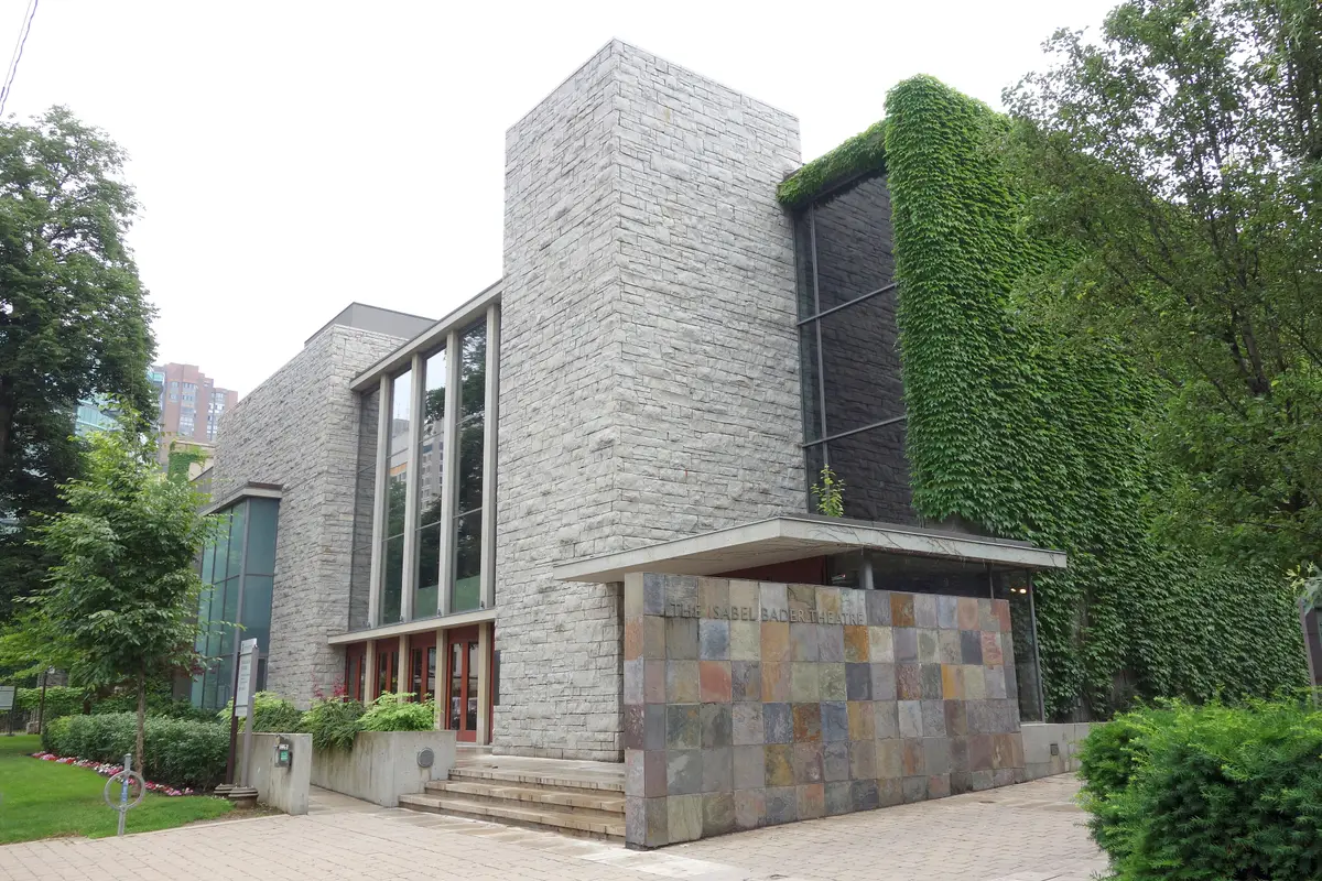 The Isabel Bader Theatre, a stone-clad building with a tiled entrance wall and ivy on one side, under a grey sky