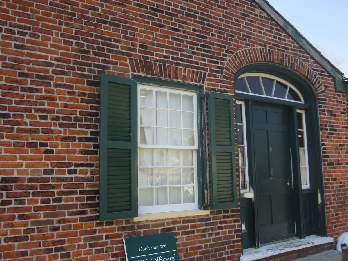 A red brick building at Fort York with green shutters and a green door under an arched window