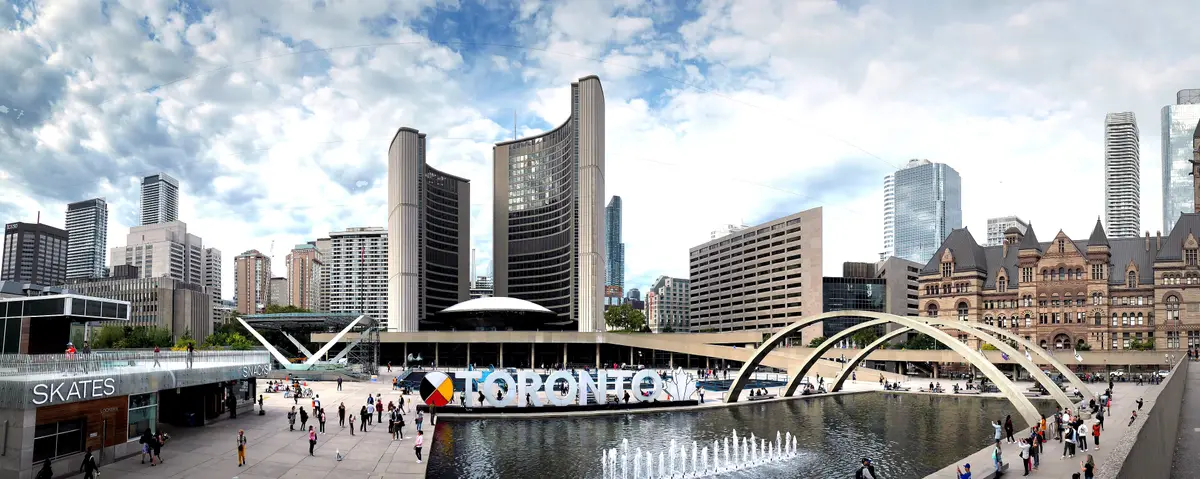 Nathan Phillips Square in full view, with City Hall's two curved towers and the low dome of the Council Chamber between them, and the TORONTO sign on the plaza