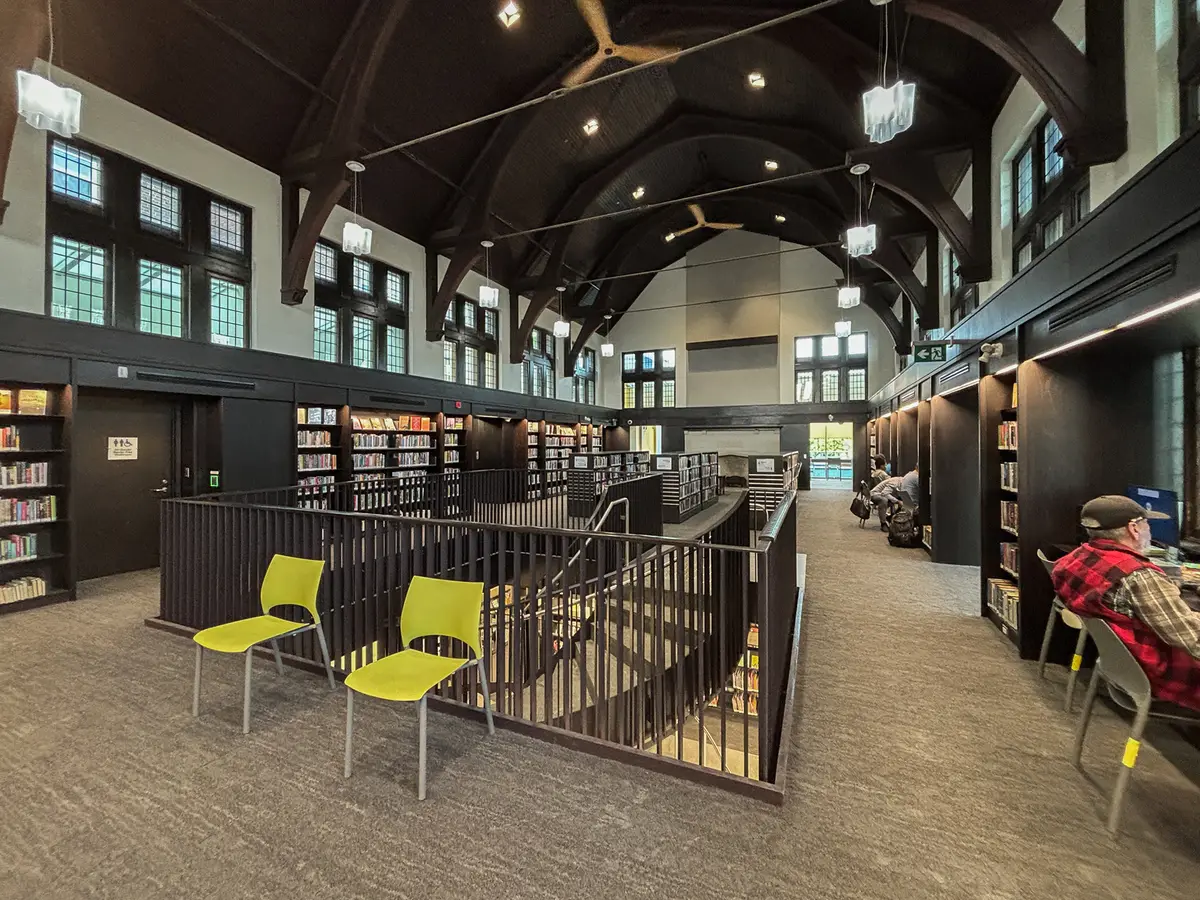 Interior of the Wychwood branch, with dark timber arches over the ceiling, leaded windows and bookshelves along the walls