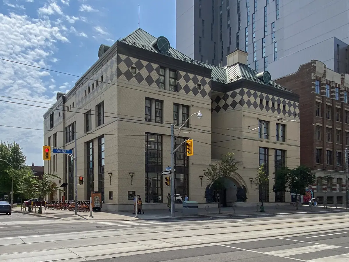 Corner view of the Lillian H. Smith branch on College Street, with a diamond-patterned facade and streetcar tracks in the foreground