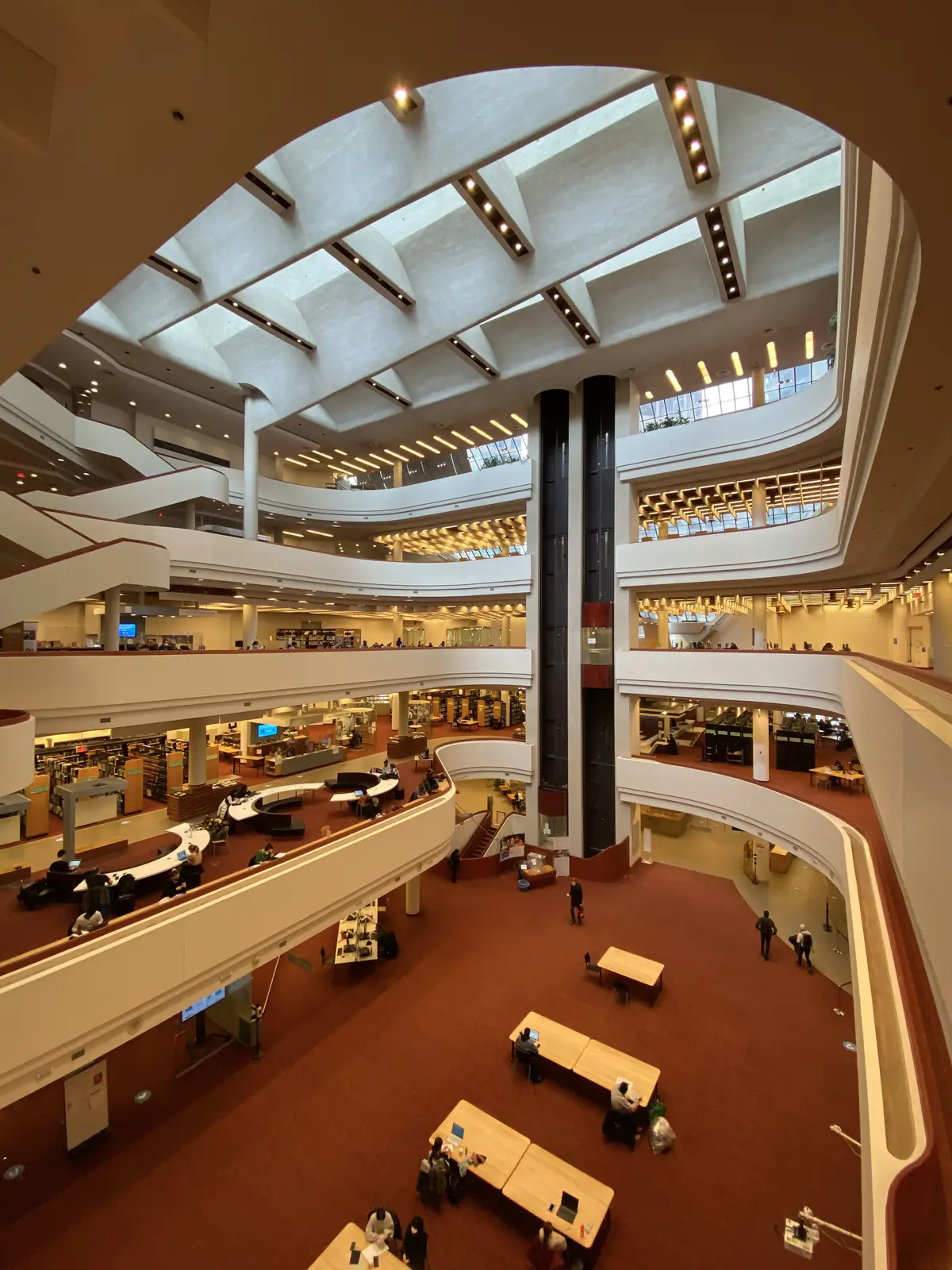 Looking down through the curved atrium of Toronto Reference Library, with tiered galleries, bookshelves and study tables