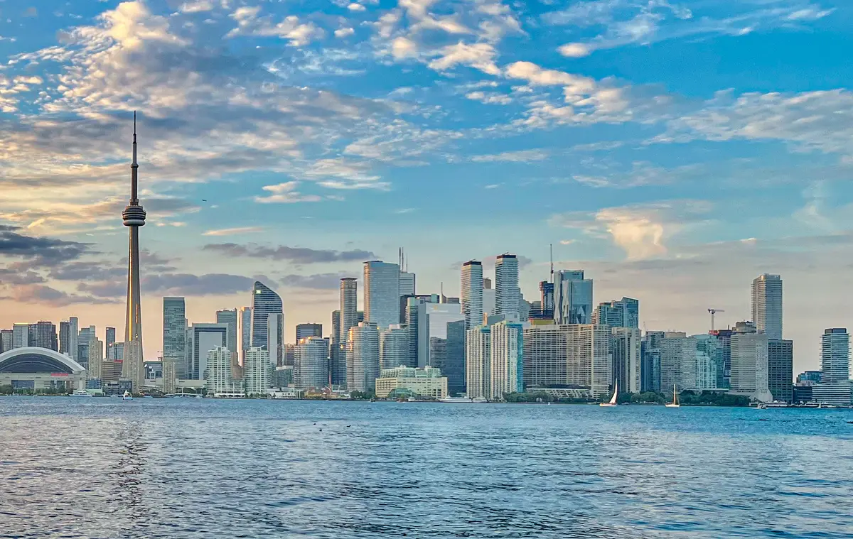 Toronto skyline with the CN Tower across open water at sunset