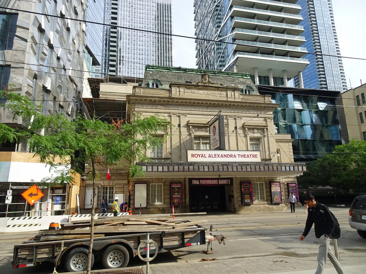 Stone facade of the Royal Alexandra Theatre, with its name banner above the entrance and glass towers behind.