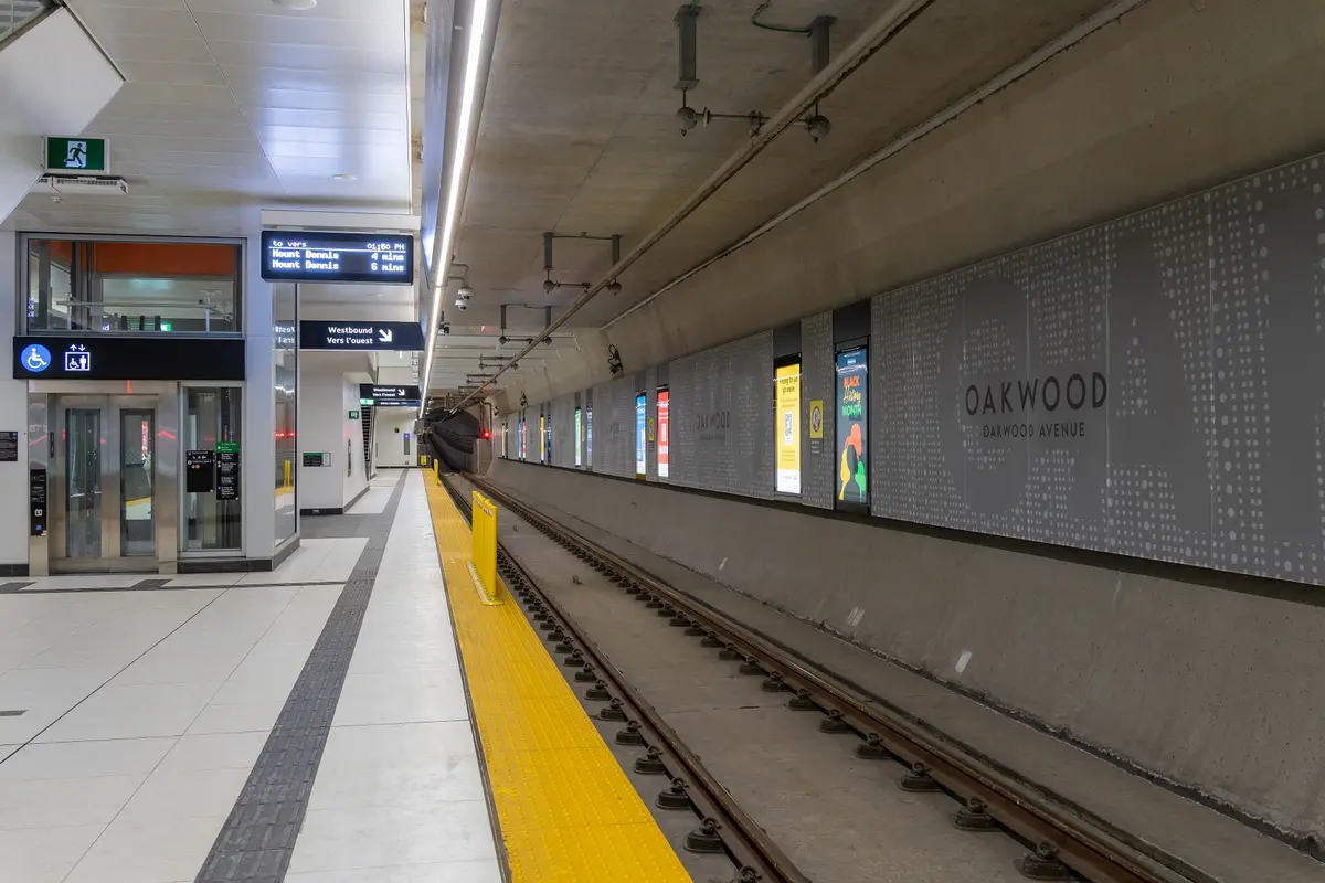 Oakwood station platform with the station name on a grey patterned wall and a tunnel ahead.