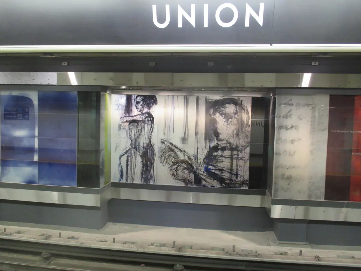 Figure drawings on glass panels along a Union Station subway platform, with the station name above.