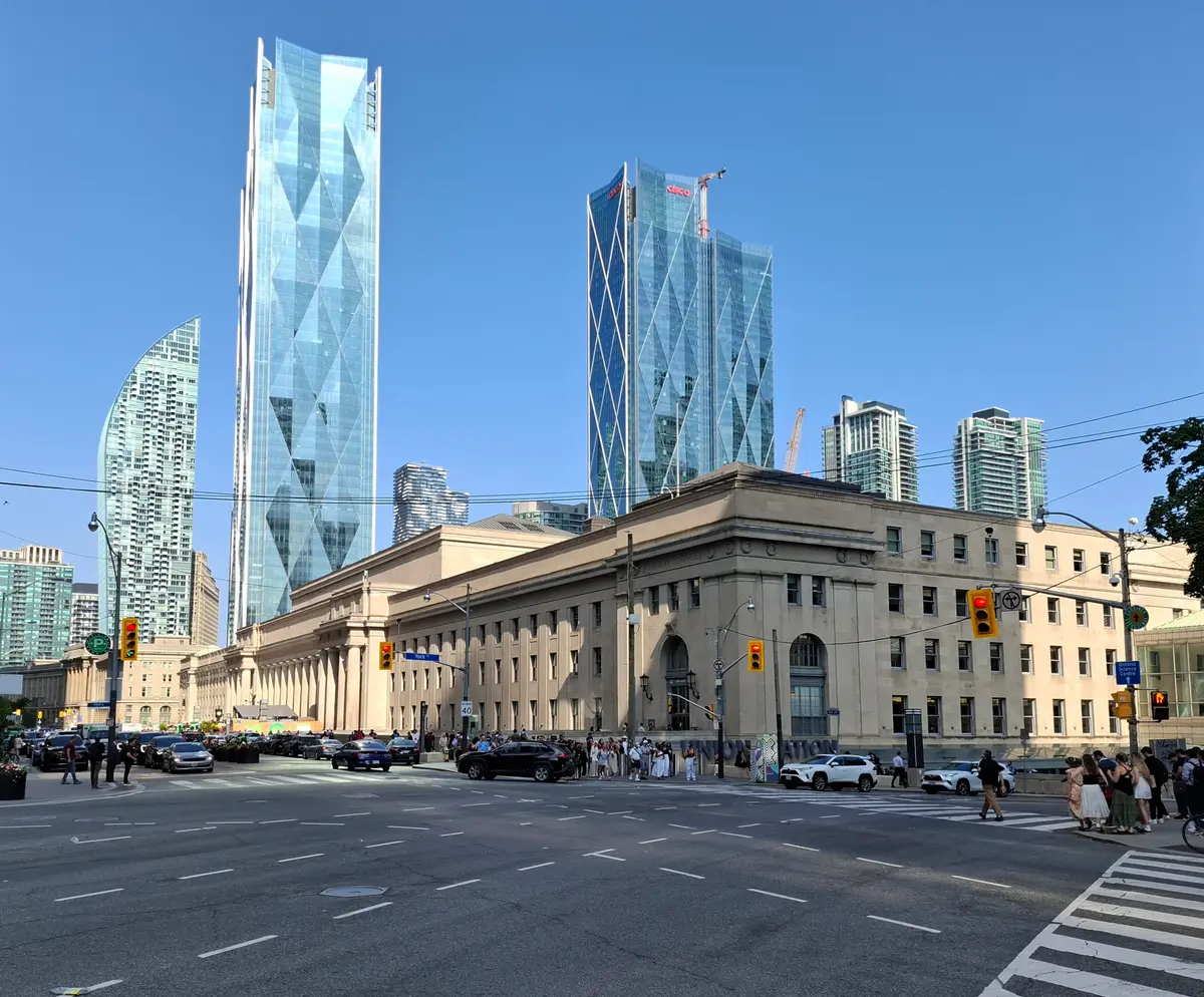 The stone facade of Union Station with glass towers rising behind it under a clear sky