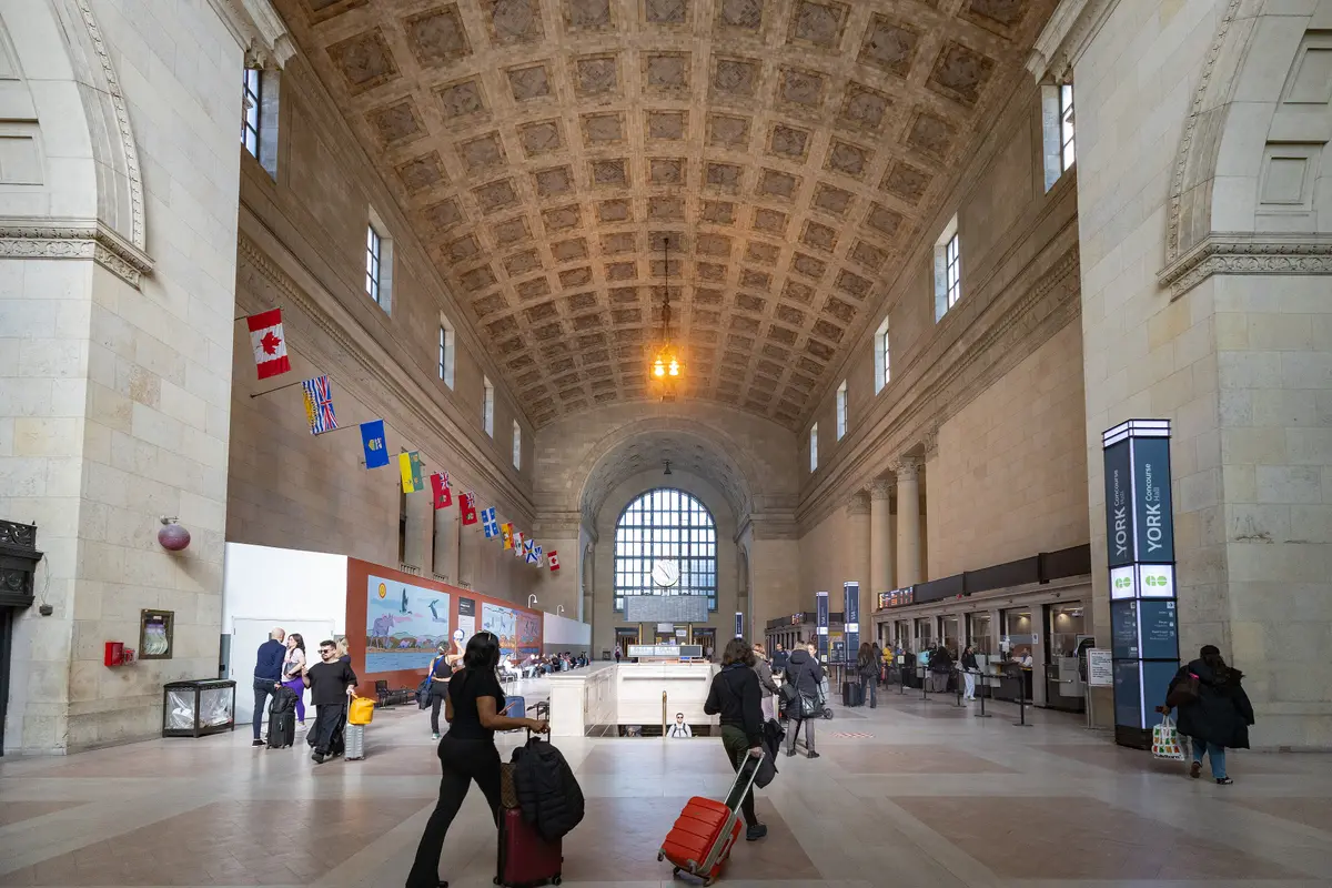 The Great Hall at Union Station, with its coffered ceiling, tall arched windows and travellers crossing the floor