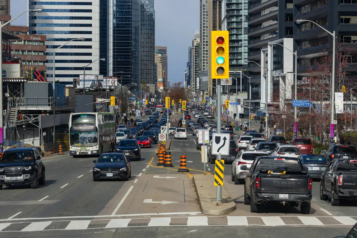 Yonge Street in North York on a clear day, lined with glass condo and office towers and a streetlit crosswalk in the foreground